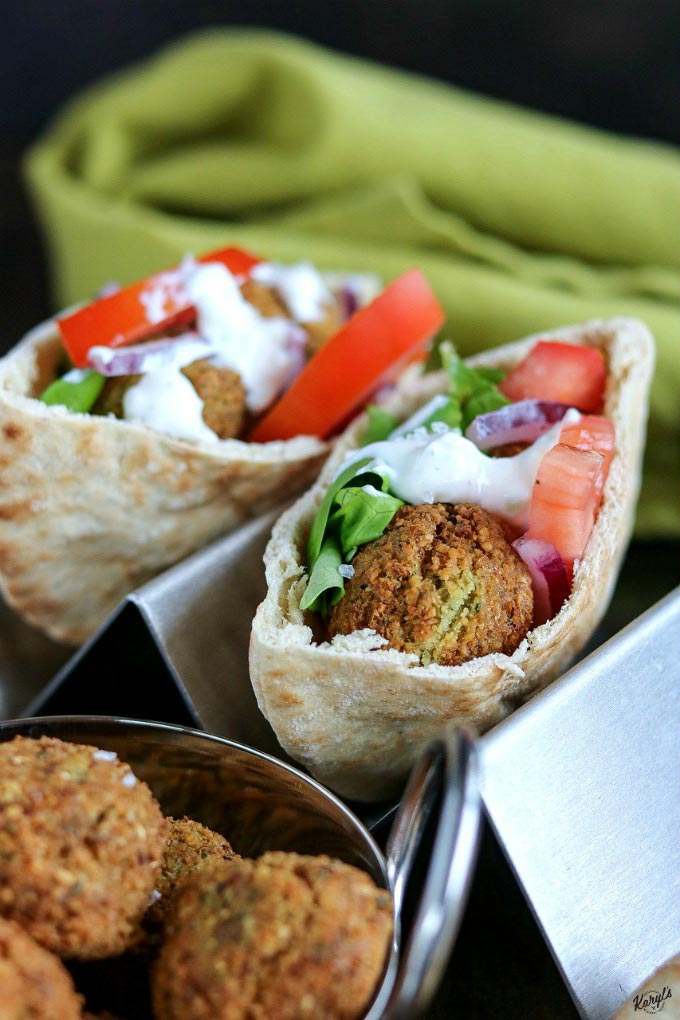close up shot of finished Falafel, 2 pita pockets filled with Falafel, tomatoes, lettuce, onion & Tzatziki sauce