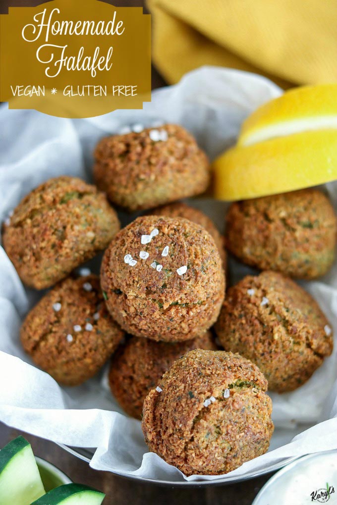 close up shot of finished Falafel in a parchment-paper lined bowl with lemon wedges on the side