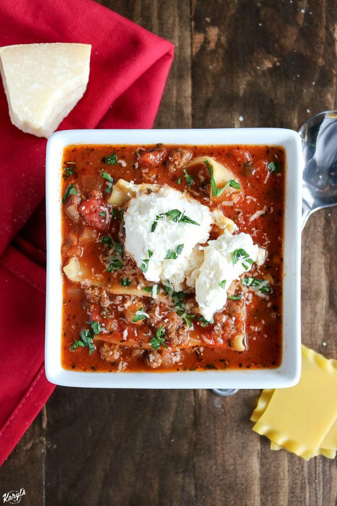 overhead shot of white bowl filled with venison lasagna soup, topped with ricotta