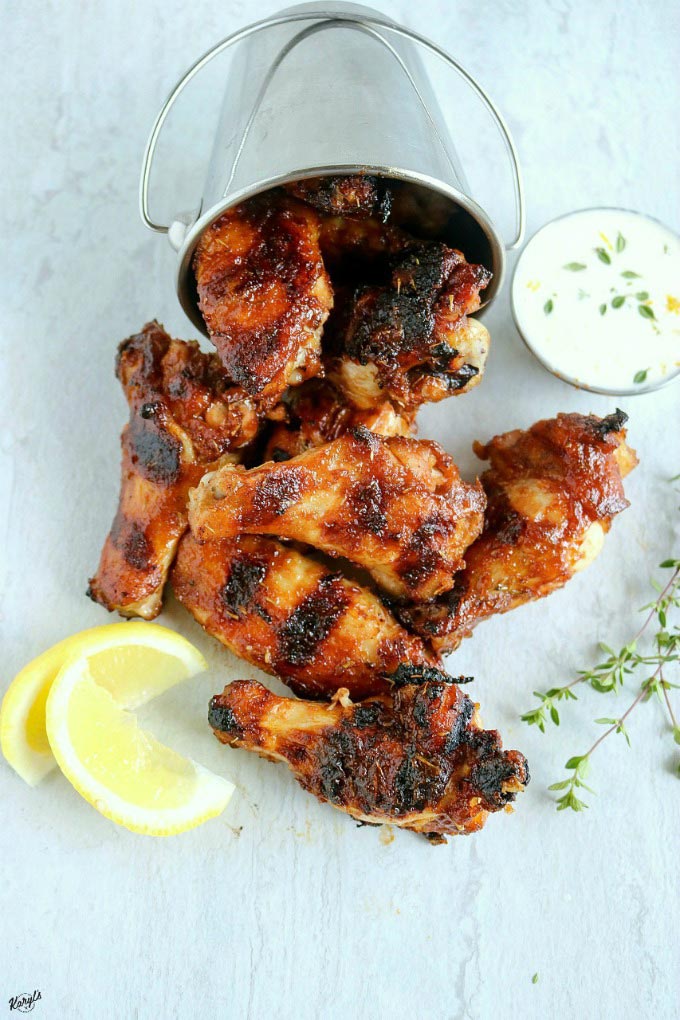 overhead shot of finished honey bourbon chicken wings in a metal bucket tipped over with wings coming out