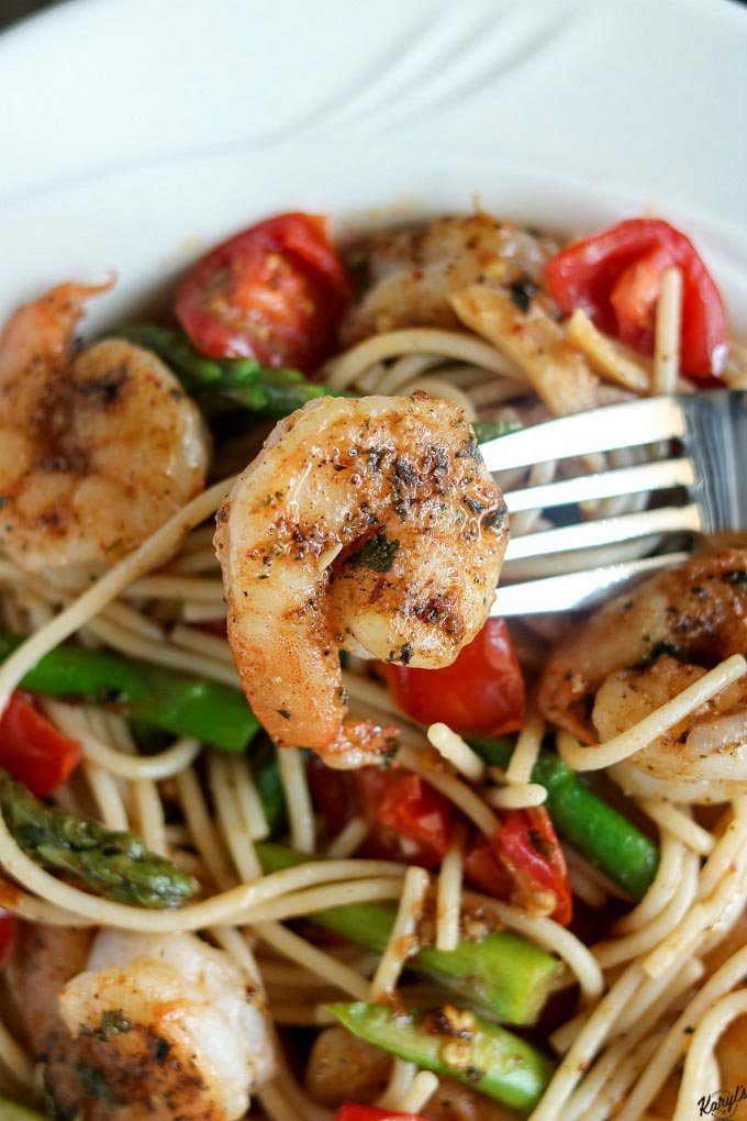 close up shot of shrimp speared by fork over bowl of Spicy Garlic Shrimp Pasta