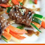 overhead shot of finished marinated steak vegetable roll ups on a white plate