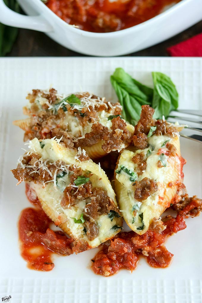 Close up shot of finished Sausage Spinach Artichoke Stuffed Shells on a white plate