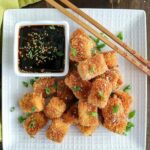 overhead shot of a pile of Pan Fried Tofu and a side of dipping sauce on a white plate
