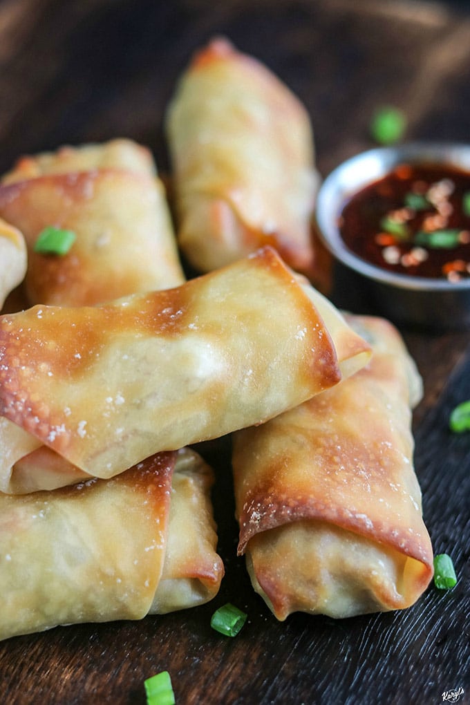 up close shot shot of egg rolls on serving board with dipping sauce