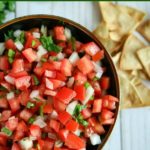 overhead shot of finished pico de gallo in a black bowl with chips on the side