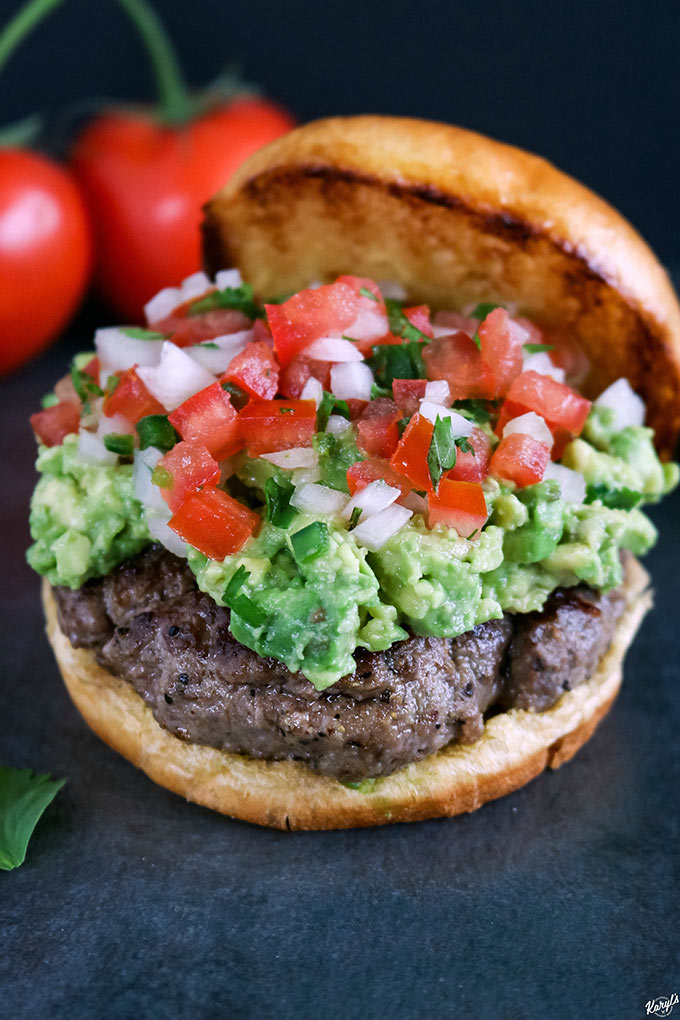 open faced finished burger, with tomatoes in background