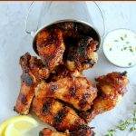 overhead shot of finished wings on a white board, the wings falling out of a metal bucket