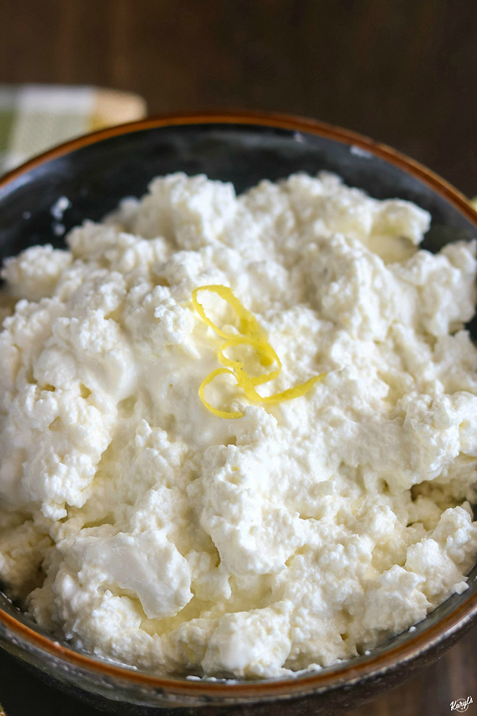 up close shot of ricotta in a black bowl with a few lemon peel strips on top