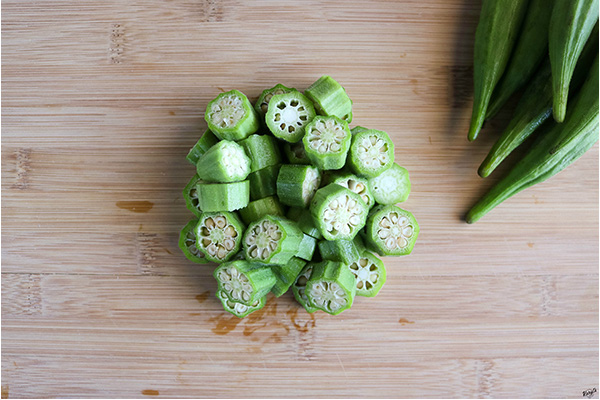 overhead process shot of cut okra on a wooden board