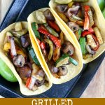 overhead shot of finished veggie fajitas in soft taco shells on a black skillet