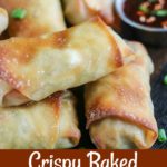 close up shot of finished egg rolls stacked on one another, with a side of dipping sauce