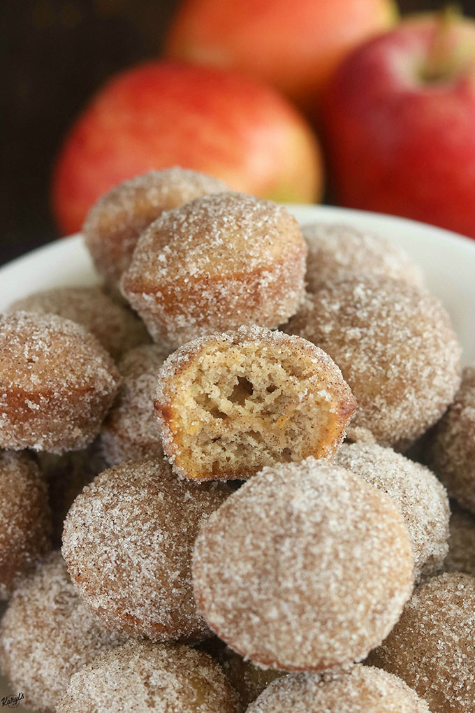 close up shot of apple cider donut holes on a white platter, with one donut hole in half