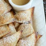 close up shot of finished wontons on a white platter with a side of dipping sauce