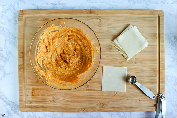overhead process shot: pumpkin mixture and wonton wrappers on a wooden board
