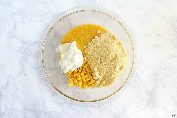 overhead process shot: corn, muffin mix, sour cream and salt in a glass bowl