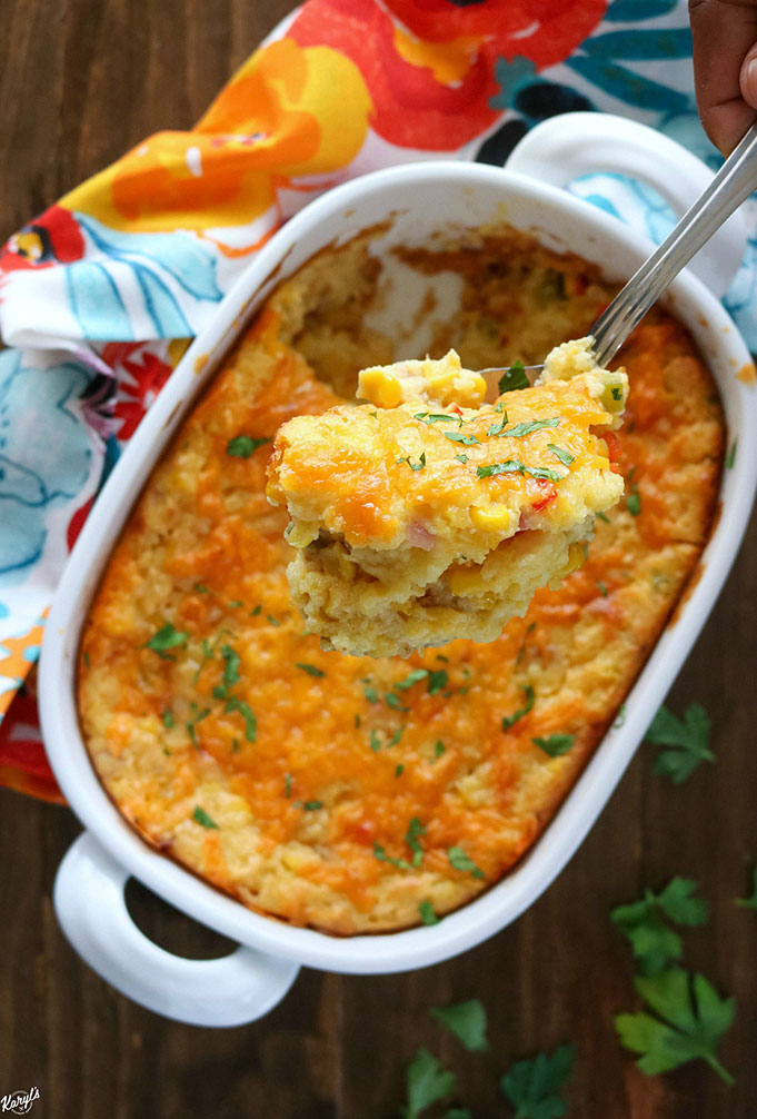 overhead shot of finished corn casserole in a white dish, with a spoon of casserole close up 