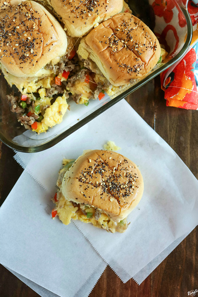 overhead shot of loaded breakfast sliders in a baking dish, with one slider out of the dish on white paper
