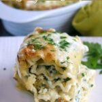 close up shot of finished spinach alfredo lasagna roll up on a white plate