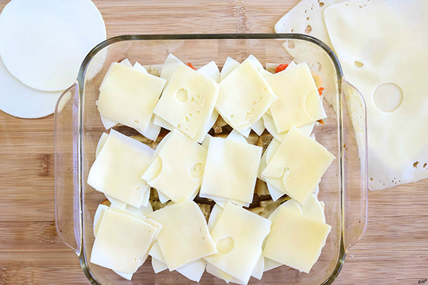 overhead process shot: provolone and Swiss cheese layered on top of olive spread