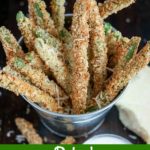 close up angle shot of finished Baked Green Bean Fries in a metal bucket with a chunk of Parmesan on the side