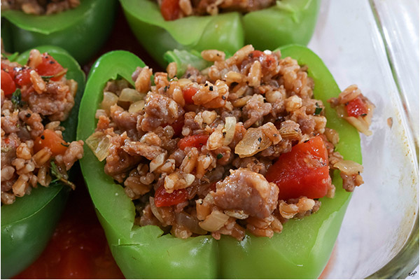 Process shot: bell peppers stuffed with mixture in a glass baking dish