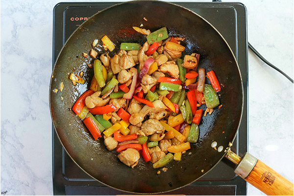 overhead process shot: cooked chicken and vegetables in a black skillet