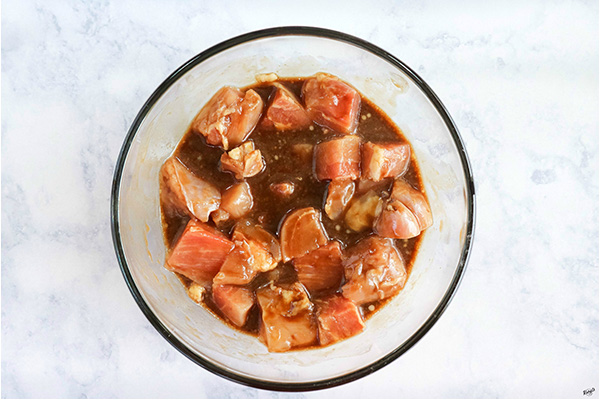 overhead process shot: chicken in marinade in a glass bowl