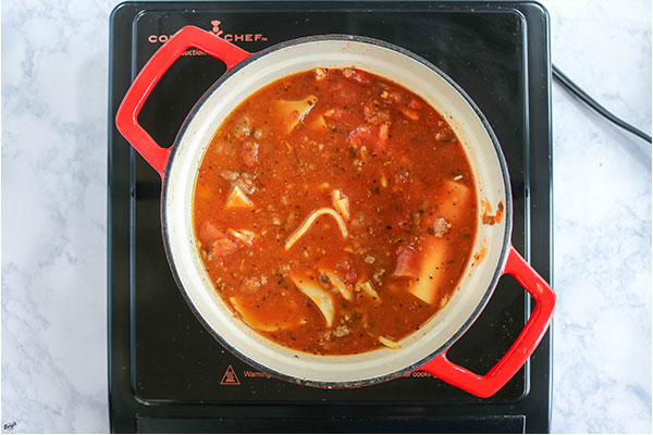 overhead process shot: venison and lasagna noodles added to the Dutch oven