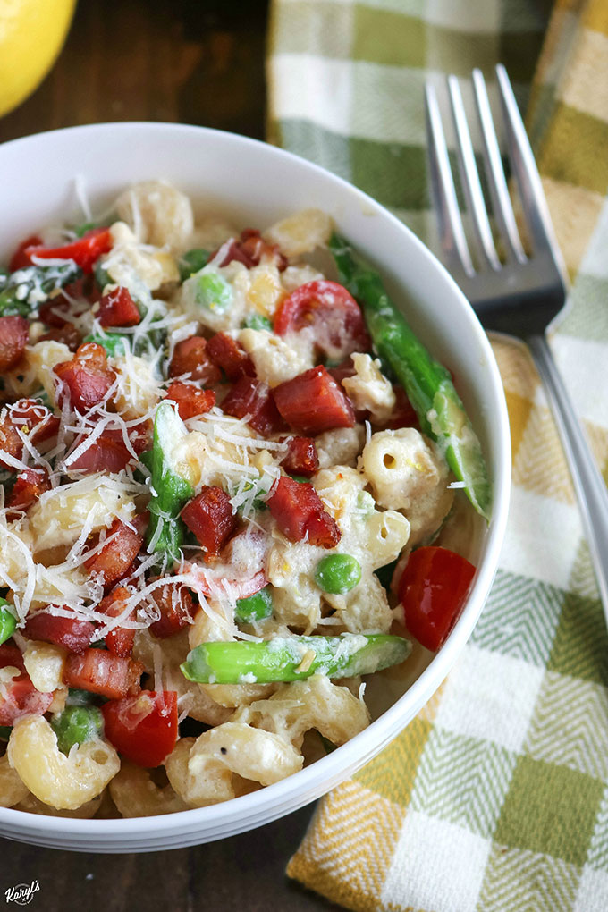 close up off center shot of finished lemon ricotta fiesta pasta in a white bowl with a fork on the side