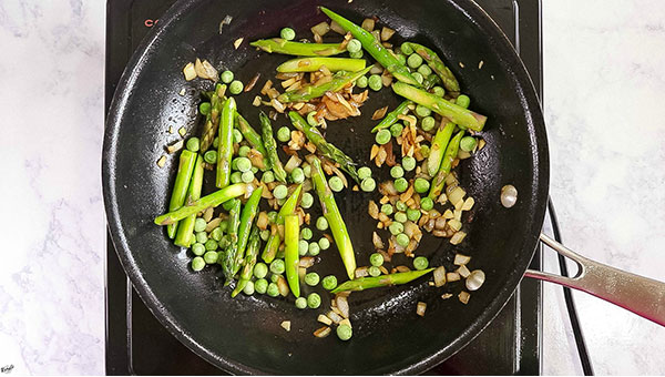 overhead process shot of vegetables cooking in a black skillet