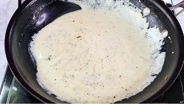 overhead process shot of lemon ricotta sauce in a black skillet