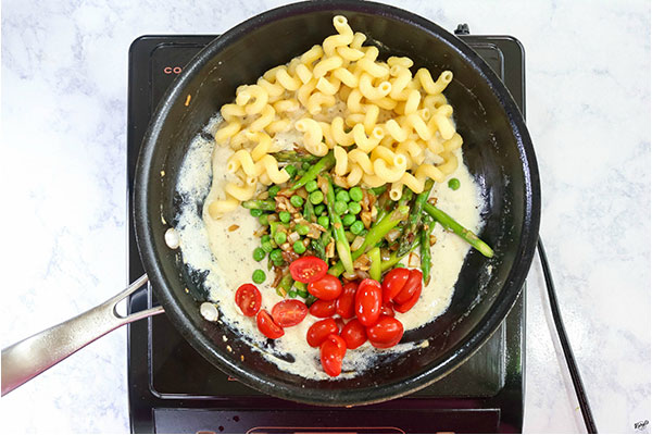 overhead process shot of pasta, and vegetables added to lemon ricotta sauce