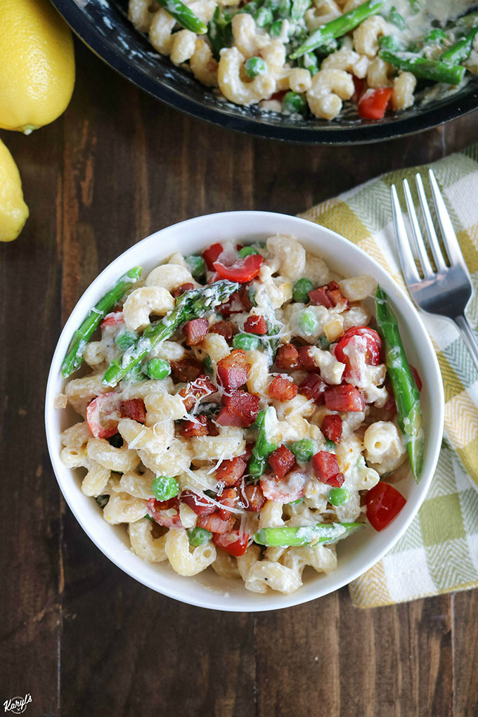 overhead shot of finished pasta in a white bowl with a skillet of extra pasta in the background