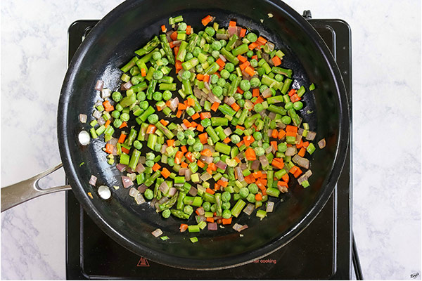 overhead process shot: all vegetables cooking in a black skillet