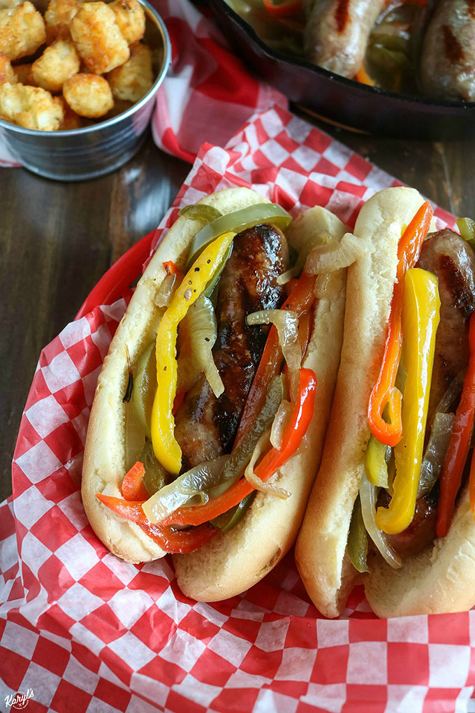 overhead shot of two finished brats in a basket with tater tots on the side