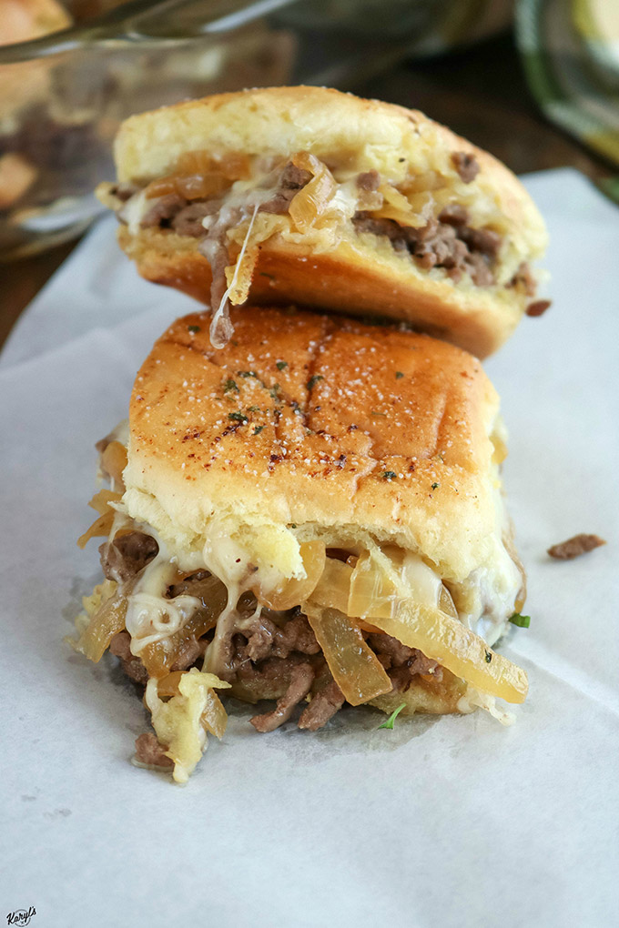 Stack of 2 finished French Onion Beef Sliders, with one falling over, on a white paper