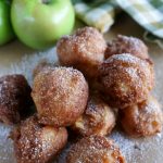 angled shot of a stack of finished Bourbon Apple Fritters on brown paper