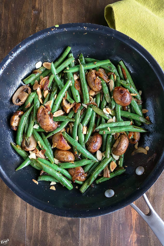 Overhead shot of finished Green Bean Mushroom Saute in a black skillet with a green napkin on the side